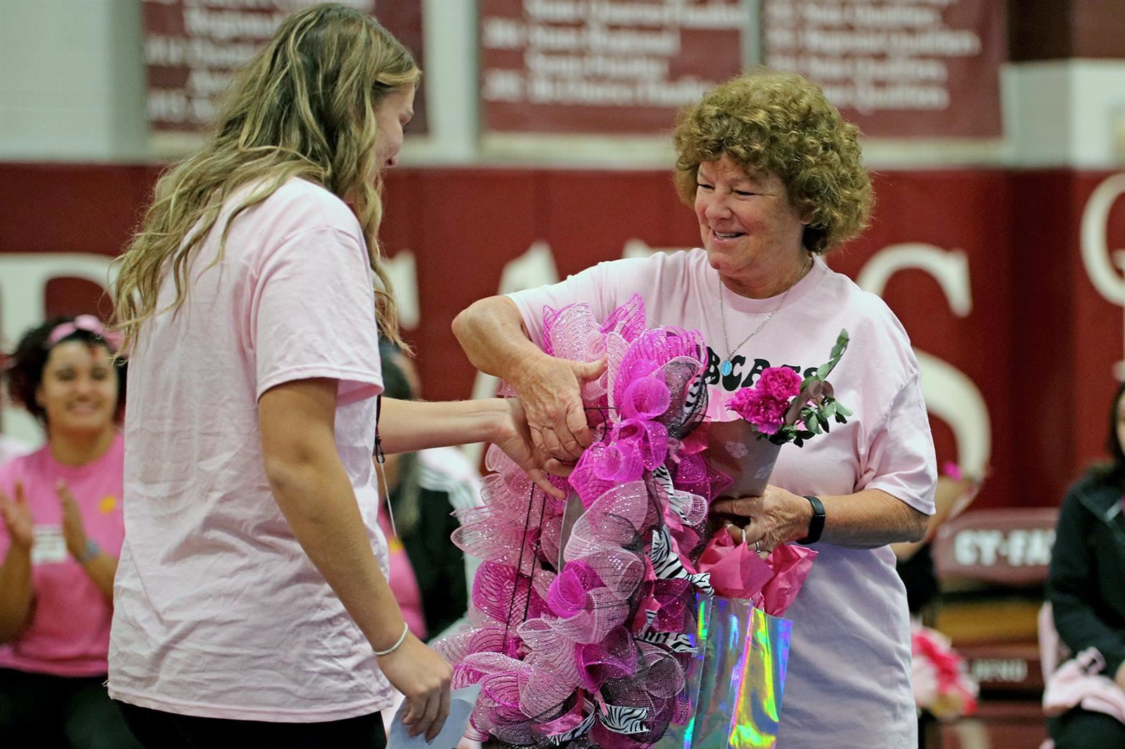 Cy-Fair basketball player Anna Farrell, left, presents former Bobcats soccer coach Bobbi Wass-Jones with a pink wreath.